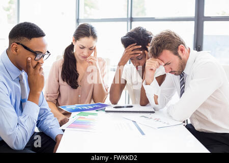 Depressed businesspeople sitting at table during a meeting Stock Photo