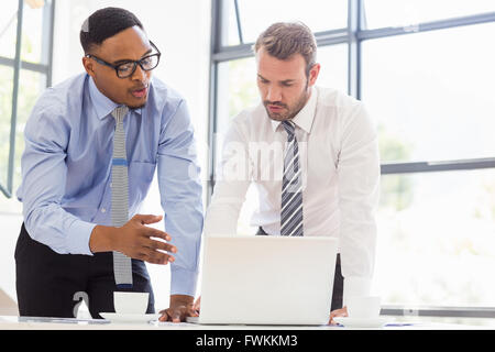 Businessmen using laptop at desk Stock Photo