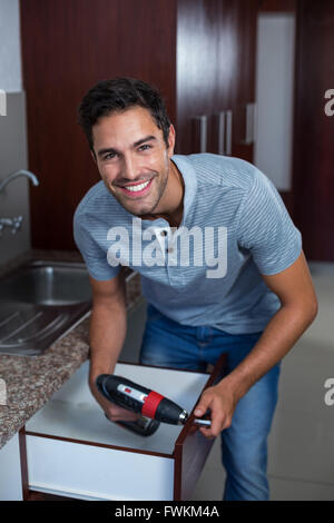 Worker using hand drill on drawer Stock Photo