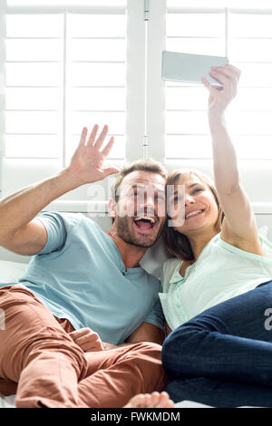 Cheerful couple taking selfie on bed Stock Photo