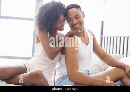 Young couple sitting together on bed Stock Photo