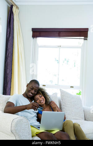 Young couple doing online shopping on laptop in living room Stock Photo