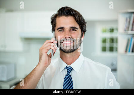 Confident businessman talking on cellphone in kitchen Stock Photo