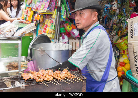 Street food vendor barbecueing chicken kebabs in Chinatown, Bangkok, Thailand Stock Photo