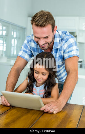 Father and daughter using digital tablet at table Stock Photo