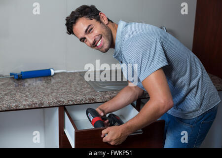 Portrait of happy man using cordless hand drill Stock Photo
