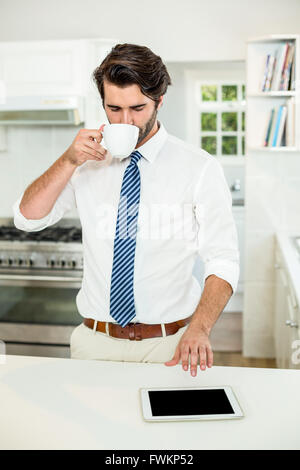 Businessman drinking coffee while using digital tablet Stock Photo