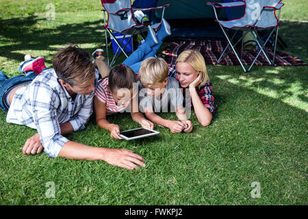 Family lying on grass and using digital tablet Stock Photo