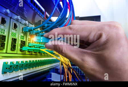 Man connecting fiber network cables to switches Stock Photo