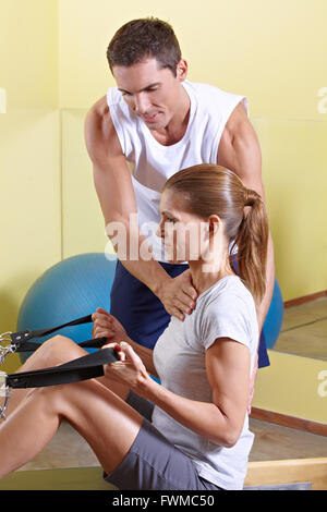 Trainer giving advice to woman in fitness centerat rowing machine Stock Photo