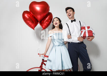 Young couple with heart-shaped balloons and gift