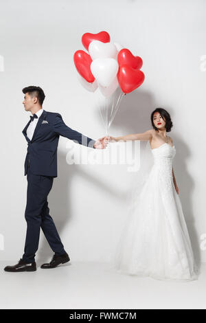 Bride and groom with bouquet and heart-shaped balloons Stock Photo