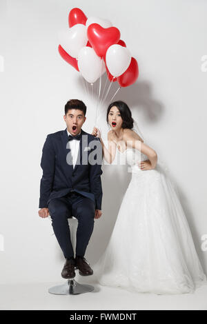 Bride and groom with bouquet and heart-shaped balloons