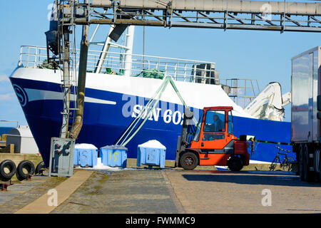 Simrishamn, Sweden - April 1, 2016: An orange forklift is lifting blue plastic crates filled with ice for use in the fishing ind Stock Photo