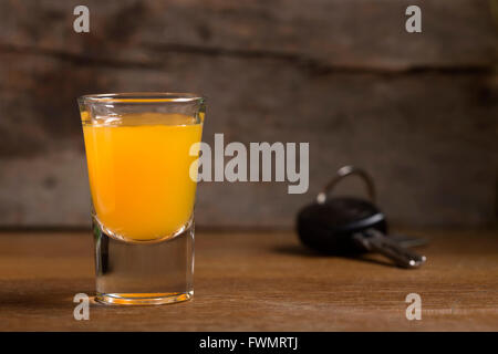 Car keys with one shot glasses over wood background - drink drive concept Stock Photo