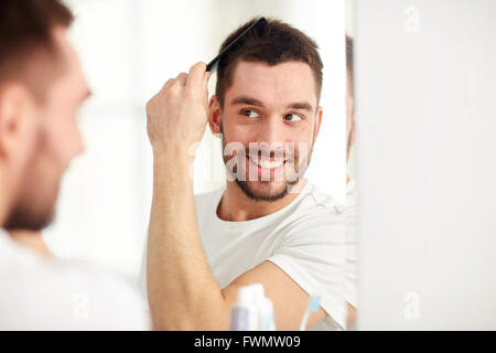 happy man brushing hair  with comb at bathroom Stock Photo