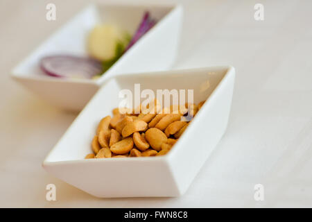 Peanuts in a white ceramic bowl on a table Stock Photo