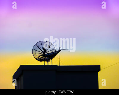 roof and satellite in the purple and orange sky evening Stock Photo