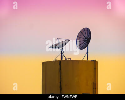 roof and twin satellite in the purple and orange sky evening Stock Photo