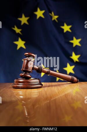 Mahogany wooden gavel on glossy wooden table. Flag of European Union, EU,  in the background.