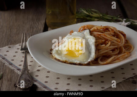 Spaghetti with tomato paste and fried egg selective focus