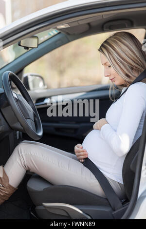 Young pregnant woman behind the steering wheel having contractions Stock Photo