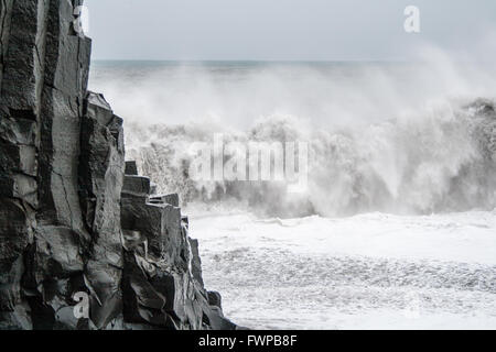 Waves crashing behind basalt column at Reynisfjara beach, near Vik Stock Photo