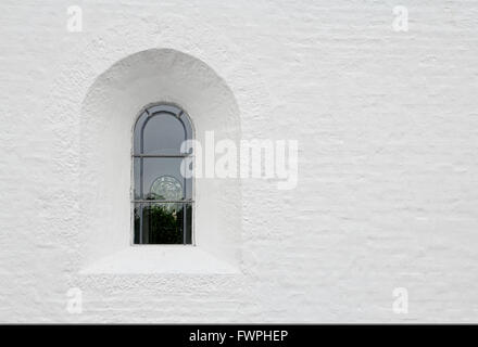 Arched leaded window in a white church wall Stock Photo