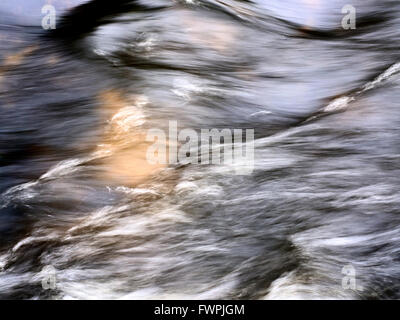 Abstract patterns formed by fast flowing water over a submerged rock in Malham Beck near Malham Yorkshire England Stock Photo