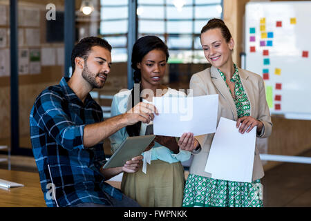 Young man and women discuss using digital tablet and document Stock Photo
