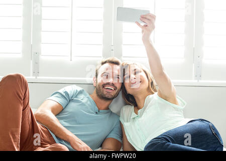 Couple taking selfie while relaxing on bed Stock Photo