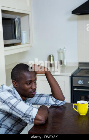 Thoughtful man leaning on table with a cup of coffee Stock Photo
