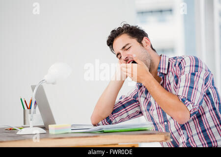 Young man yawning at his desk Stock Photo