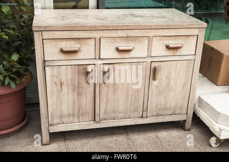 Standard old wooden chest of drawers stands on the street Stock Photo