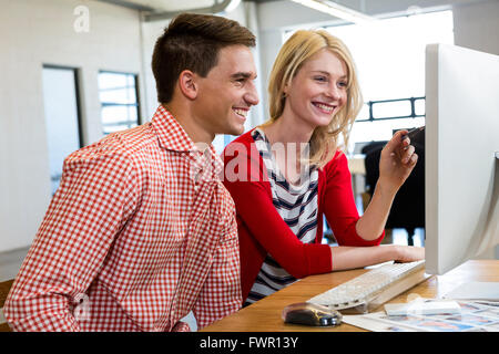 Colleagues working on computer and discussing Stock Photo