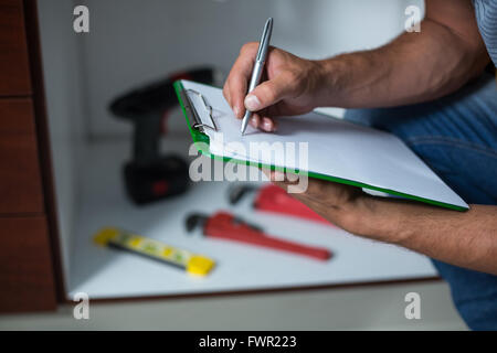 Midsection of man writing on clipboard Stock Photo
