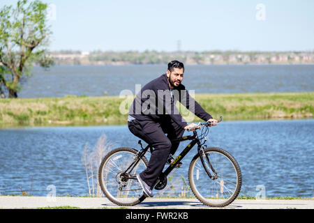 A Hispanic man bicycles for exercise on the trails next to the North Canadian river and Overholser Lake, Oklahoma City,USA. Stock Photo