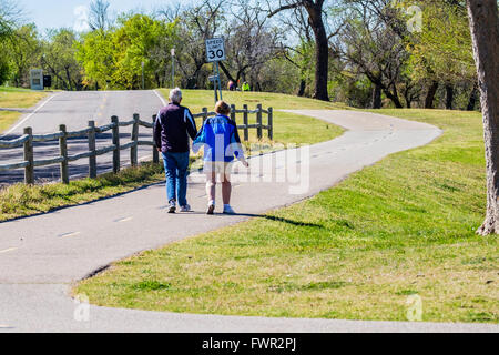 A senior Caucasian couple hold hands and walk on the trails at Overholser lake in Oklahoma City, Oklahoma, USA. Stock Photo