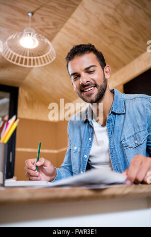 Smiling man in office writing in a notepad Stock Photo