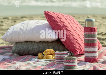 Breakfast on the beach. Coffee and croissants on the sea. Pillows, slipcover a thermos bottle and Cup - hand-knitting. Stock Photo