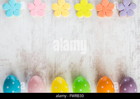 Colorful easter eggs and homemade fondant covered flower cookies on a white wood background Stock Photo