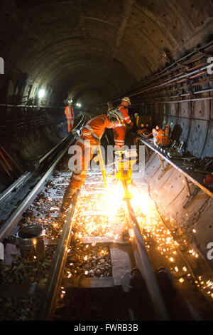 Engineers grinding replacement track components after using thermite welding on London Underground rail track, London, UK Stock Photo