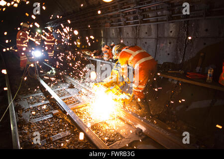 Engineers grinding replacement track components after using thermite welding on London Underground rail track, London, UK Stock Photo