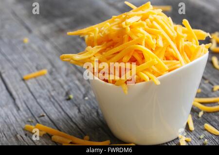 Shredded cheddar cheese in white cup  close up Stock Photo