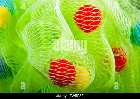 Close up of green mesh bath puff with red and yellow baubles Stock Photo