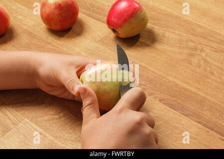 Hands peeling an apple more apples waiting to be peeled Stock Photo