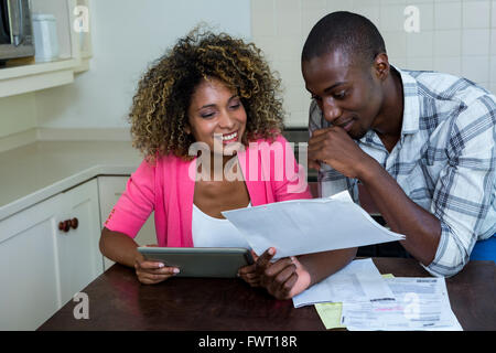 Happy couple checking bills while using digital tablet Stock Photo