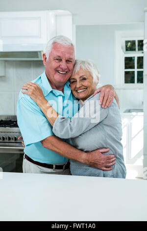 Cheerful senior couple hugging in kitchen Stock Photo