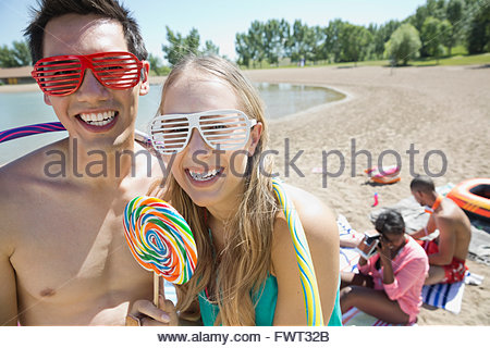 Portrait of cheerful couple in novelty sunglasses with lollipop