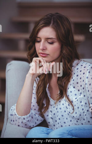 Thoughtful woman sitting on sofa Stock Photo